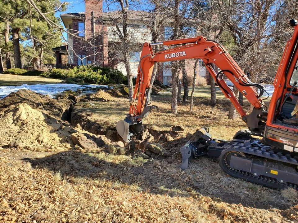 excavator digging a line out from house